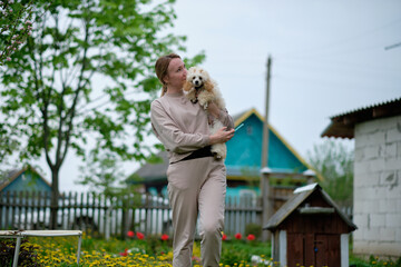 a small apricot poodle in the arms of a woman in the garden