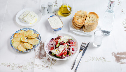 Greek food background. Ouzo, Greek salad, tzatziki, assortment of feta. Top view. Traditional Greek taverna menu. Close up