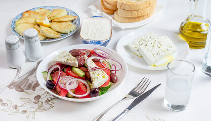 Greek food background. Ouzo, Greek salad, tzatziki, assortment of feta. Top view. Traditional Greek taverna menu. Close up