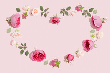 Creative flowers composition. Heart symbol made of pink rose flowers on pastel pink background. Minimal flat lay.