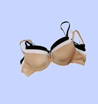 Stack of women's bras with molded cups on a blue background, bra. Lingerie push up, classic colors: white, black, beige.