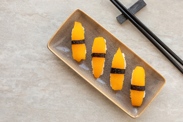Vegan sushi nigiri with golden tomato instead of salmon fish. Top view.