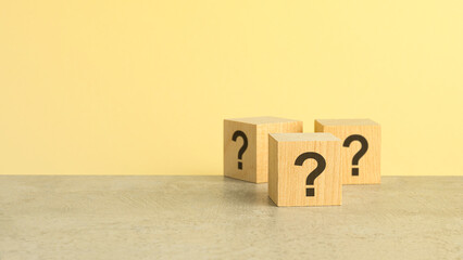 Cube with question mark on wooden background. Space for text