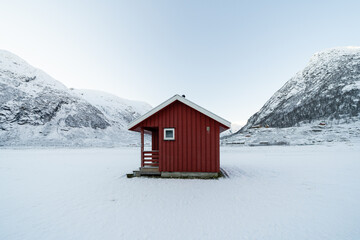 A red wooden house made of planks in the snowy mountains of Norway in winter