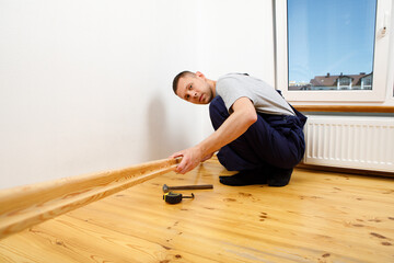 To make repairs. Installing a new skirting board. a man makes repairs in a room