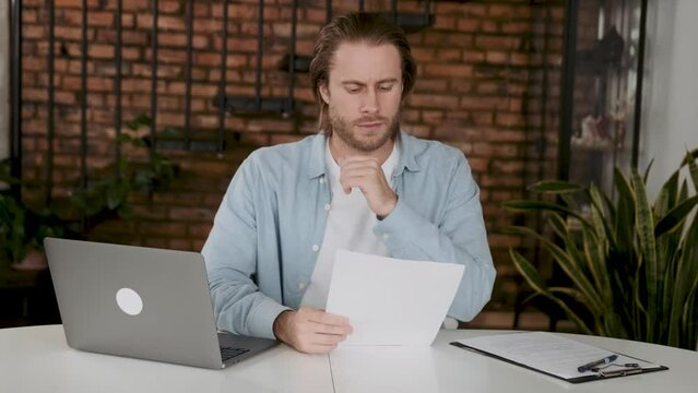 concentrated man reading contract sitting at the desk. Employee reading a document in the office