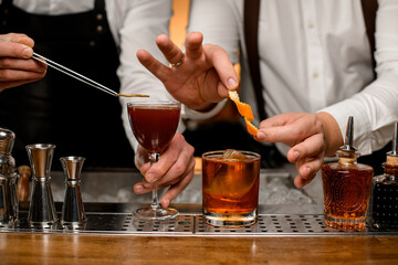 close-up on glasses with drinks that bartenders decorate with orange zest and a dry slice of lemon
