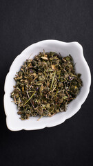 dried thyme lies in a saucer on a black background