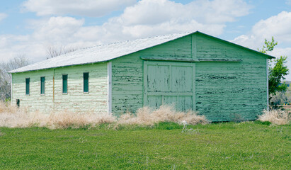 Green clapboard out-building or garage on a farm in Wyoming is used for equipment and supplies. The paint is peeling.
