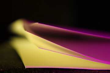 Papeles de oficina para documentos despegados entre si, con luz de color rasante, con borde en lìnea y desenfoque hacia atràs, forma un original diseño abstracto en bokeh con fondo negro