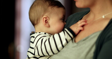 Baby holding mother necklace. Mom holding toddler infant in arms