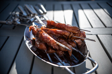 Grill skewers with marinated chicken in a metal bowl.