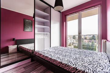 Stylowa sypialnia z dużym łóżkiem i fioletowymi ścianami - obrazy, fototapety, plakaty