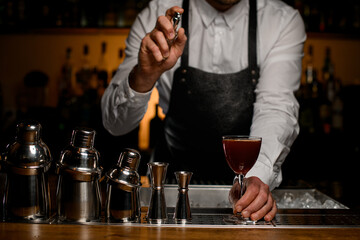view of row of shakers and male hand holding glass of drink and sprinkles on it