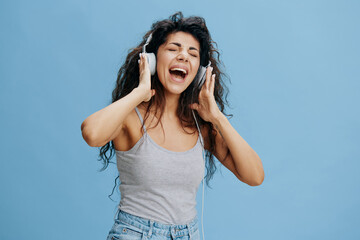 MUSIC STREAMING PLATFORM AD CONCEPT. Enjoyed beautiful Latin female touch headphones, sing, scream. Cool offer for Phone pc fashion brands karaoke ad. Studio shoot isolated with blue sky background