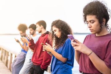 Group of multiracial friends using smartphones to sharing content on social networks. Technology lifestyle concept - Selective focus.