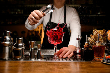 great view on bar counter with a variety of bar equipment and goblet with splashing drink