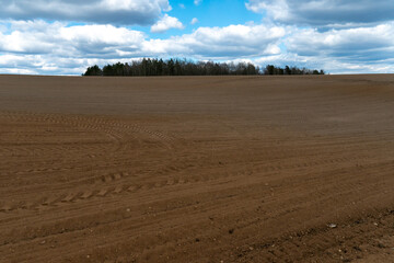 A plowed field against the sky. The season of planting crops in a wheat field. Preparing the field for planting rapeseed, wheat, rye and barley in rural areas.