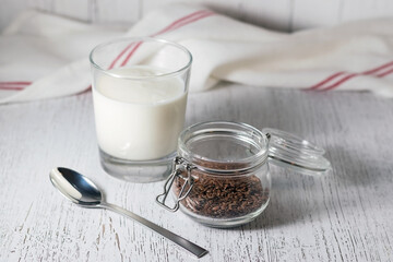 Kefir or yogurt in a glass with flax seeds on a white wooden background. Healthy diet.