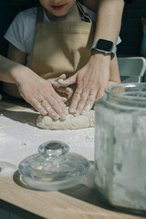 Mom teaching daughter to rolling dough on kitchen table. Young girl helping mother on kitchen.