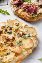 Assortment of Roman pizzas with baked pears, blue cheese and walnuts, as well as with slices of beef and arugula and grated cheese