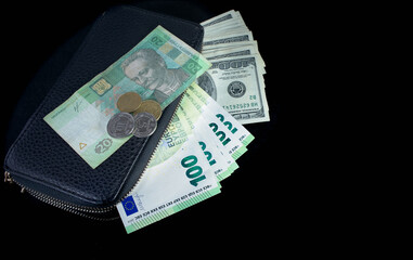 Ukrainian hryvnia, euros and dollars in a black wallet on a black background