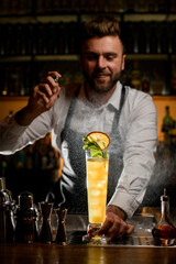 view of tall glass with drink on the bar counter and a male bartender accurate splashes on it