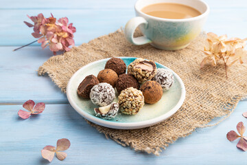 Chocolate truffle candies with cup of coffee on a blue wooden background. side view, close up.