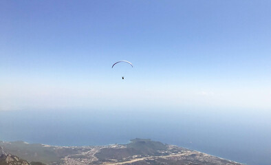 paragliding in the open sky, outdoor activities, travel in a warm country. bright parachute for a man. travel against the backdrop of high mountains