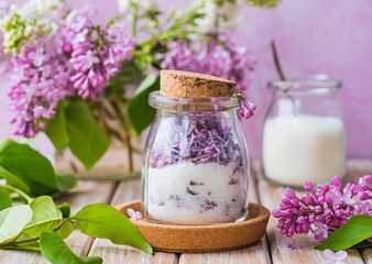 Obraz na płótnie Canvas Flavored sugar with lilac flowers in a transparent glass jar on a wooden background. The use of edible wild plants and flowers in cooking.