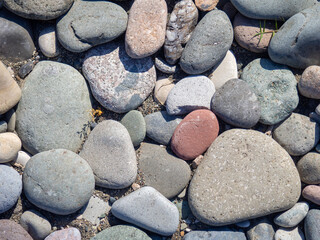 Background from multicolored pebbles. Black sand. Pebble coast. Stone beach. Stone pattern.