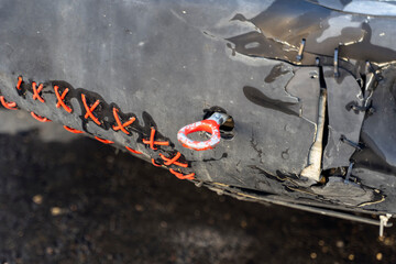 The plastic bumper of the car is repaired with wire and ties