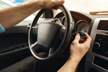 Naklejka premium Man driving new car in city, turning on windshield wipers