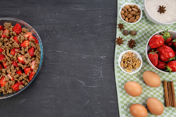 Fruit strawberry crumble preparation on black concrete table background, top view. Space for text, copy space. Tasty juicy berries.