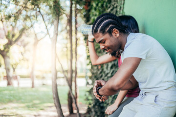 side view of african american young man checking sportwatch