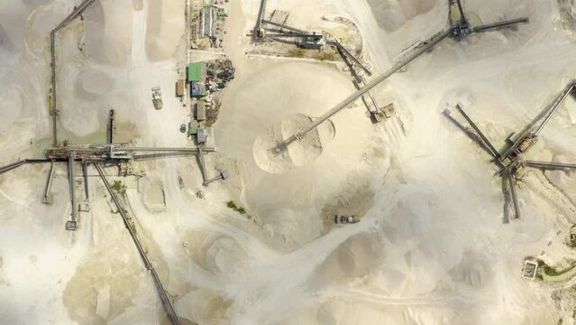 Aerial view of sand quarry, industrial extraction of a sand for construction industry. Excavators and tractors load crushed stone and rock into dump trucks. 4K. Separation of sand in construction. 