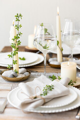 Rustic zero waste wedding decor with natural elements. Wooden table, candles, linen napkins, branches with green leaves. Eco-friendly decoration for the special dinner. Romantic and cozy place