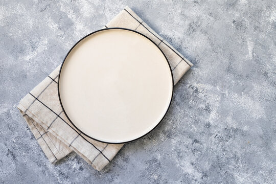Empty white plate and towel on gray concrete background. Top view, with copy space