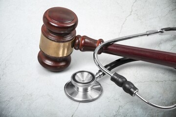 Judge gavel and medical stethoscope on wooden desk. Health and Law concept.