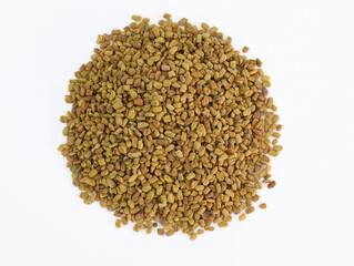 Pile of Fenugreek seeds on white background. Many whole fenugreek seeds close up, culinary ingredient.
