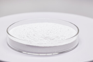 Petri dish with powdered Benzoyl Peroxide, used in the preparation of cream, lotion or gel in the treatment of acne and mild and moderate forms of dermatitis. Isolated white background, copy space