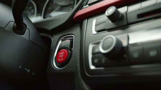 A female finger with a red manicure presses the red car start button and starts the sport automobile. Slow motion pressing the ignition button of a modern keyless car. 4k footage