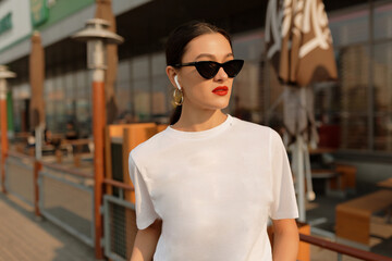 Outdoor portrait of stylish brunette woman with red lips enjoying summer evening. Debonair trendy lady in sunglasses looking forward.