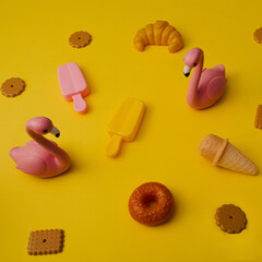 Summer time, flamingos and sweets - croissants, cookies, ice cream on a bright yellow background