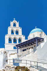 White church with a blue dome on Santorini island in Greece. Hot summer sun day.