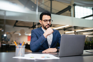Smart pensive handsome young middle eastern businessman with beard in glasses