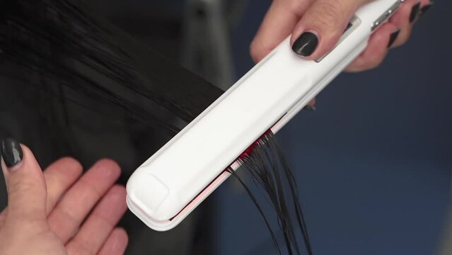 the cosmetologist treats the patient's hair and also straightens the hair. using ultraviolet light. black hair. plus size. beauty parlor