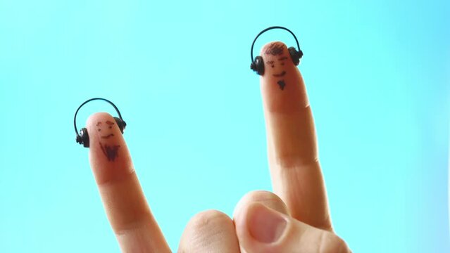 A beared pinky and index finger in headphones nod to the beat of the music