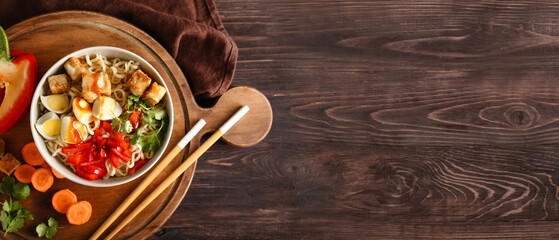 Bowl of tasty Chinese noodles with chicken on wooden background with space for text