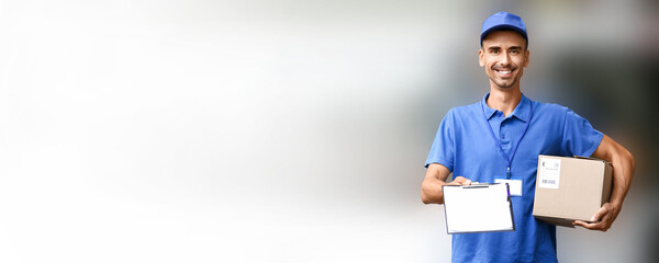 Male courier holding parcel on blurred background with space for text